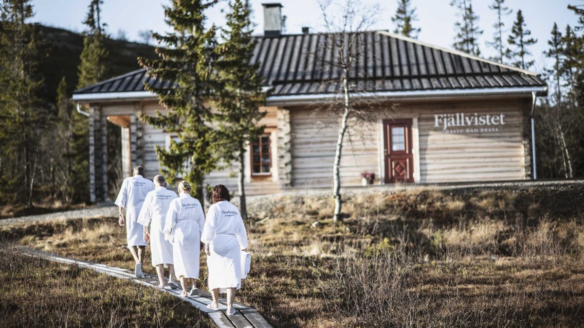 Besökare i morgonrock gåendes på väg mot Fjällvistet
