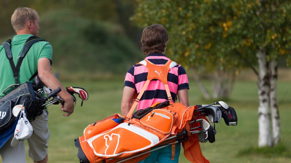 Golfspelare som bär sina golfbagar