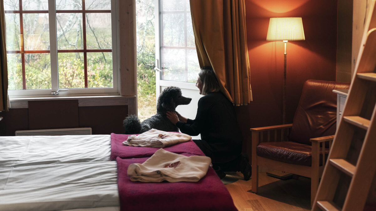 Kvinna och hund vid altandörren på ett hundvänligt hotellrum på Storhogna Högfjällshotell & Spa