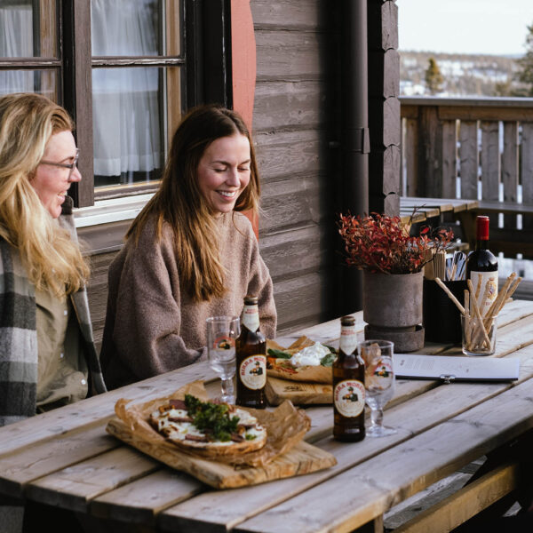 Fyra glada kvinnor njuter av italienska delikatesser på fjällsidans uteservering