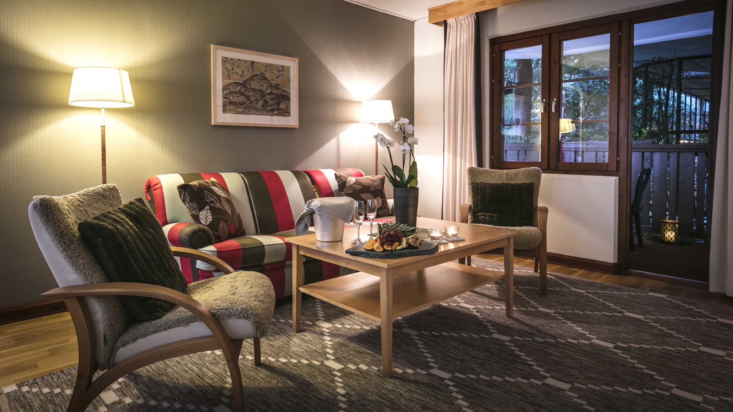 Sällskapsrum med soffa, fåtölj och mysig belysning i sviten på Storhogna Högfjällshotell & Spa